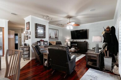 Living room featuring ornamental molding, a ceiling fan, and wood finished floors