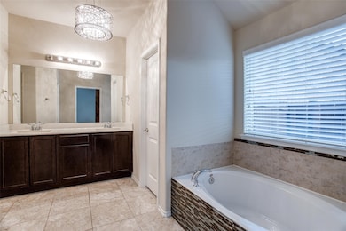 Full bathroom with double vanity, light tile patterned floors, and a bath