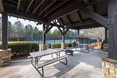 View of patio with a tennis court and an outdoor fire pit