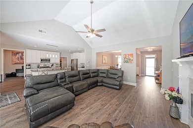 Living area with ceiling fan, wood finished floors, high vaulted ceiling, and baseboards