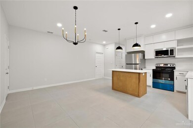 Kitchen featuring appliances with stainless steel finishes, a center island, light countertops, white cabinetry, and open shelves