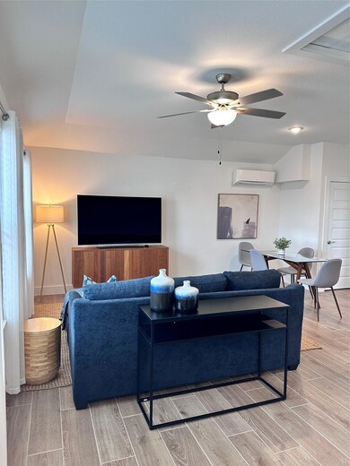 Living room with wood finish floors, a wall unit 
