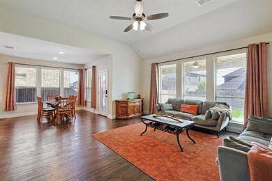 Living room featuring ceiling fan, lofted ceiling, hand-scraped hardwood  and a healthy amount of sunlight