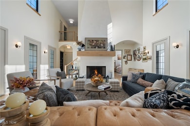 Living room featuring arched walkways, healthy amount of natural light, a high end fireplace, and a towering ceiling