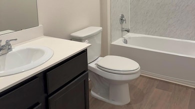 Full bathroom with wood-type flooring, toilet, vanity, and shower / washtub combination