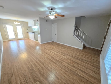 Unfurnished living room with light wood-type flooring, ceiling fan, stairs, and a chandelier