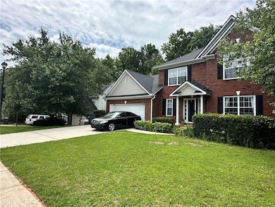 View of front facade with brick siding, concrete driveway, a front yard, and a garage