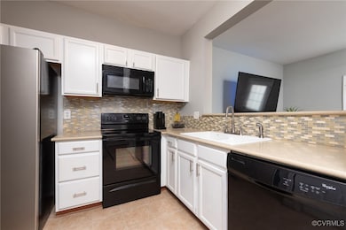 Kitchen featuring black appliances, a sink, light