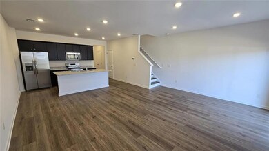 Kitchen with appliances with stainless steel finishes, dark cabinets, an island with sink, dark wood finished floors, and open floor plan