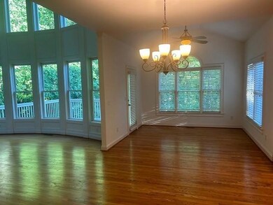 Unfurnished dining area featuring vaulted ceiling, wood finished floors, a chandelier, and baseboards