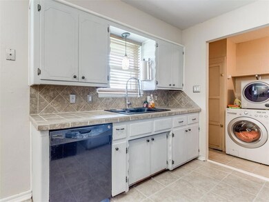 Kitchen featuring black dishwasher, backsplash, li