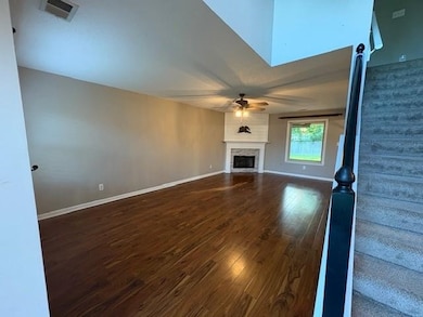 Unfurnished living room featuring a ceiling fan, wood finished floors, and a fireplace