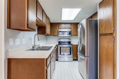 Kitchen featuring light floors, stainless steel appliances, light countertops, and brown cabinets