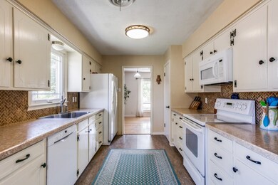 Kitchen white cabinets and white appliances. Large sink with a window