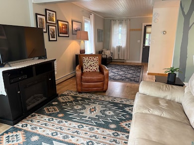Living area with baseboard heating, wood finished floors, and wooden ceiling