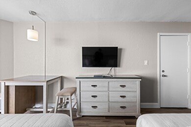 Bedroom with dark wood-style floors, a textured wall, and a textured ceiling