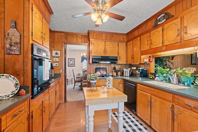Kitchen with a sink, black appliances, wooden wall