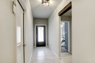 Enter through the glass and wood front door to the tiled entry with high ceilings and wood beam accented doorways.