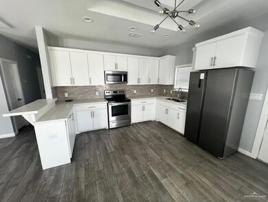 Kitchen with white cabinetry, kitchen peninsula, and appliances with stainless steel finishes