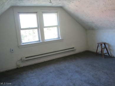 3rd flr Additional living space with vaulted ceiling, a textured ceiling, baseboard heating, and carpet