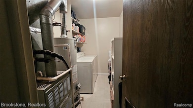 Laundry room featuring washing machine and dryer, water heater, and light tile patterned floors