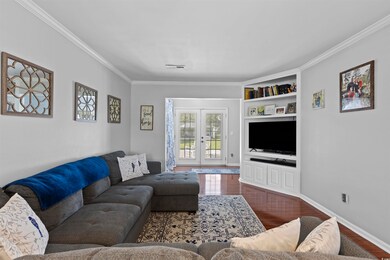 Living area with dark wood-style floors, crown mol