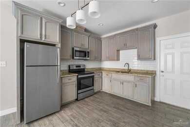 Kitchen with stainless steel appliances, a sink, light stone countertops, tasteful backsplash, and wood finished floors