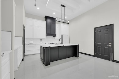 Kitchen featuring freestanding refrigerator, light countertops, white cabinetry, hanging light fixtures, and recessed lighting