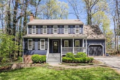 Colonial home with a front lawn, driveway, a chimn