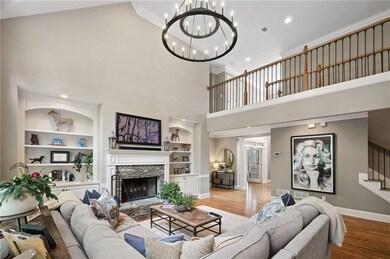 Living area with built in shelves, a towering ceiling, baseboards, wood finished floors, and a chandelier