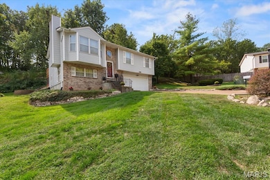 Bi-level home featuring brick siding, a chimney, a garage, and view of scattered trees