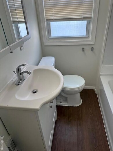 Full bathroom featuring dark wood finished floors, a tub to relax in, and vanity