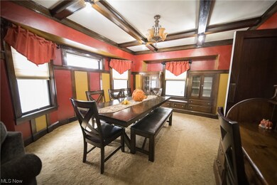 Carpeted dining room featuring plenty of natural light, beamed ceiling, coffered ceiling, and a chandelier