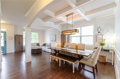 Living room featuring arched walkways, decorative columns, crown molding, dark wood finished floors, and stairway