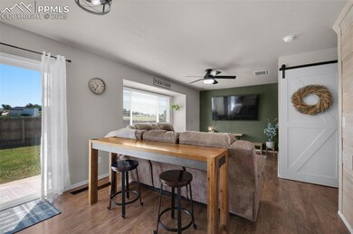 Living room featuring ceiling fan, a barn door, and wood finished floors