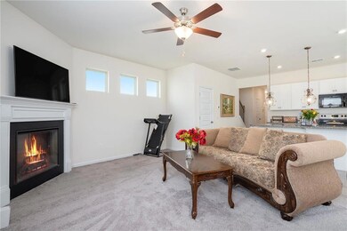 Living area featuring light colored carpet, ceiling fan, a glass covered fireplace, recessed lighting, and baseboards