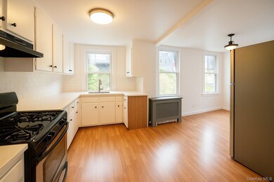 Kitchen with gas range oven, light countertops, radiator, and light wood finished floors