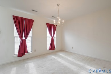 Carpeted empty room with a chandelier and baseboards