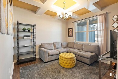 Living area featuring coffered ceiling, beamed ceiling, wood finished floors, and a chandelier