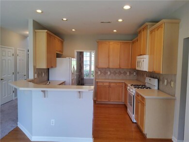 Kitchen with light countertops, backsplash, a breakfast bar area, a peninsula, and white appliances
