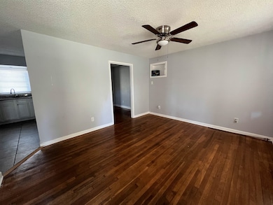 Unfurnished room with a textured ceiling, dark wood-type flooring, and ceiling fan