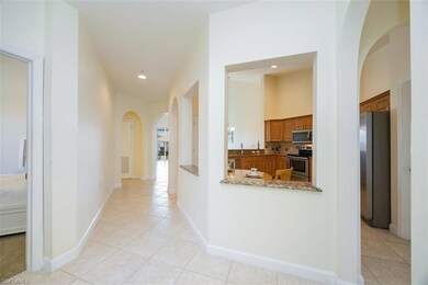 Hall featuring arched walkways, recessed lighting, and light tile patterned flooring