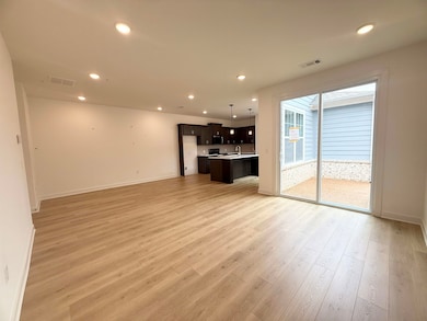 Unfurnished living room featuring light wood-type flooring, recessed lighting, baseboards, and a sink
