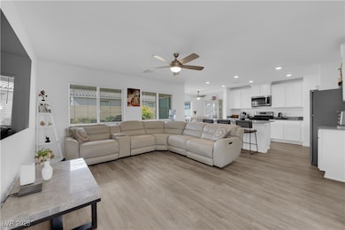Living room with light wood finished floors, recessed lighting, and a ceiling fan