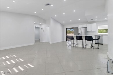 Kitchen with lofted ceiling, a breakfast bar area, white cabinets, a center island, and stainless steel appliances