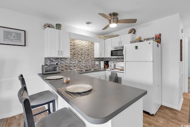 Kitchen featuring dark countertops, white appliances, tasteful backsplash, and a textured ceiling