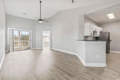 Kitchen with high vaulted ceiling, light wood-style flooring, white cabinetry, open floor plan, and ceiling fan