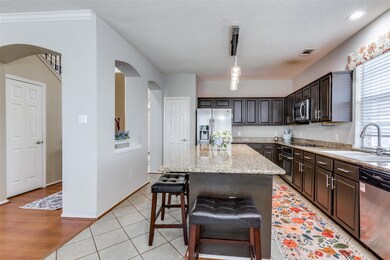Kitchen featuring a huge granite island, lots of countertops and cabinets with hardware, stainless steel appliances and pretty lighting.