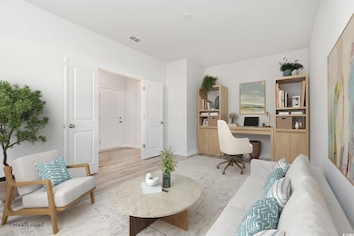 Office space featuring light wood-style floors and built in study area. Virtually staged.