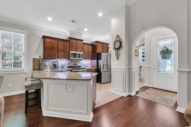 Kitchen featuring appliances with stainless steel finishes, a sink, light stone counters, a breakfast bar, and arched walkways